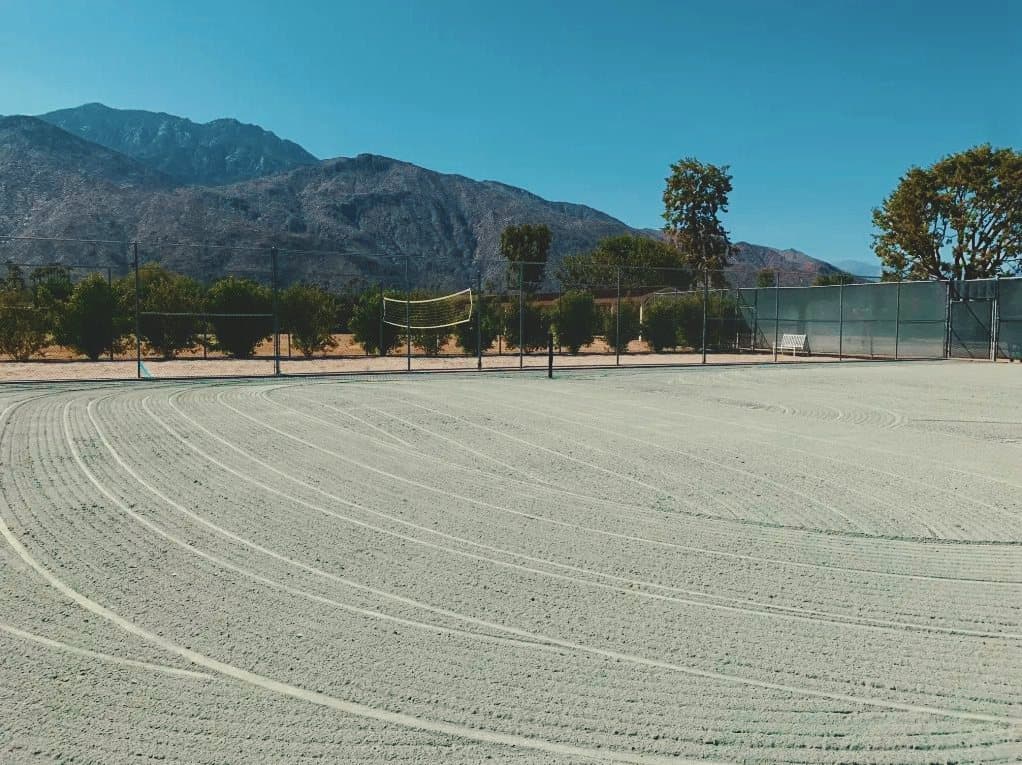 A clay court surface raked in long curved passes during a renovation